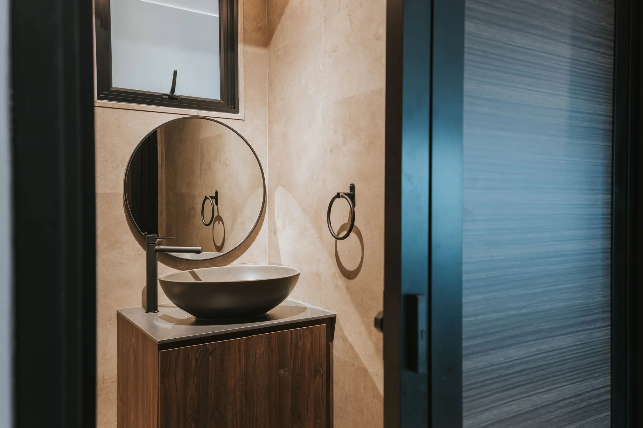 Stone-look bathroom with a round mirror at 213C Punggol Walk