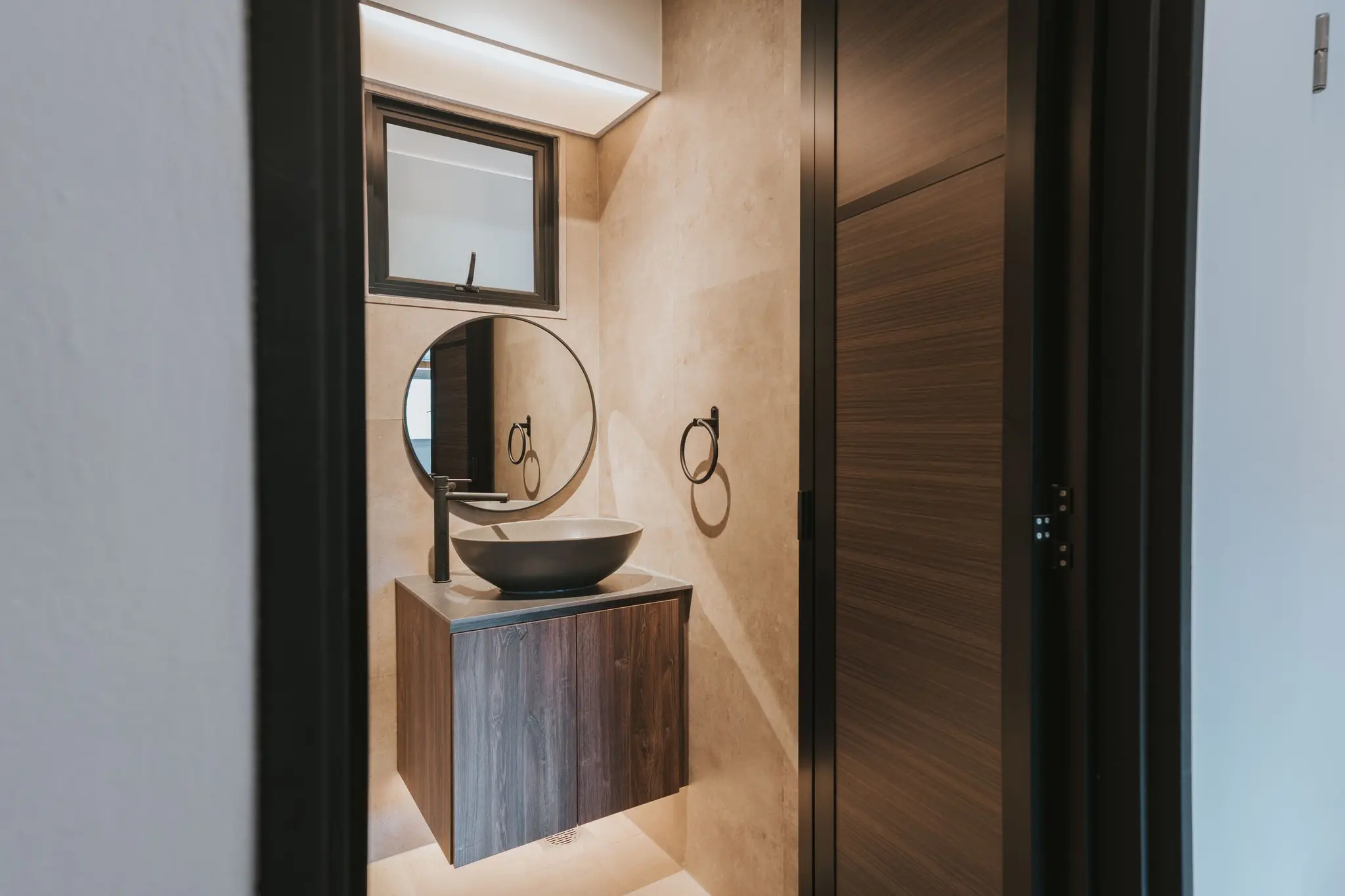Stone-look bathroom with a round mirror at 213C Punggol Walk