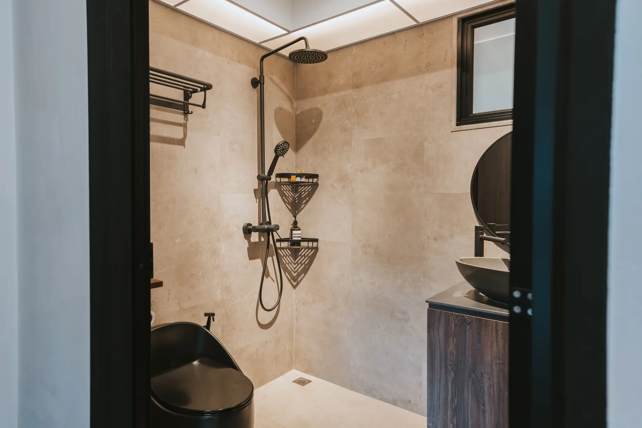 Stone-look bathroom with a round mirror at 213C Punggol Walk