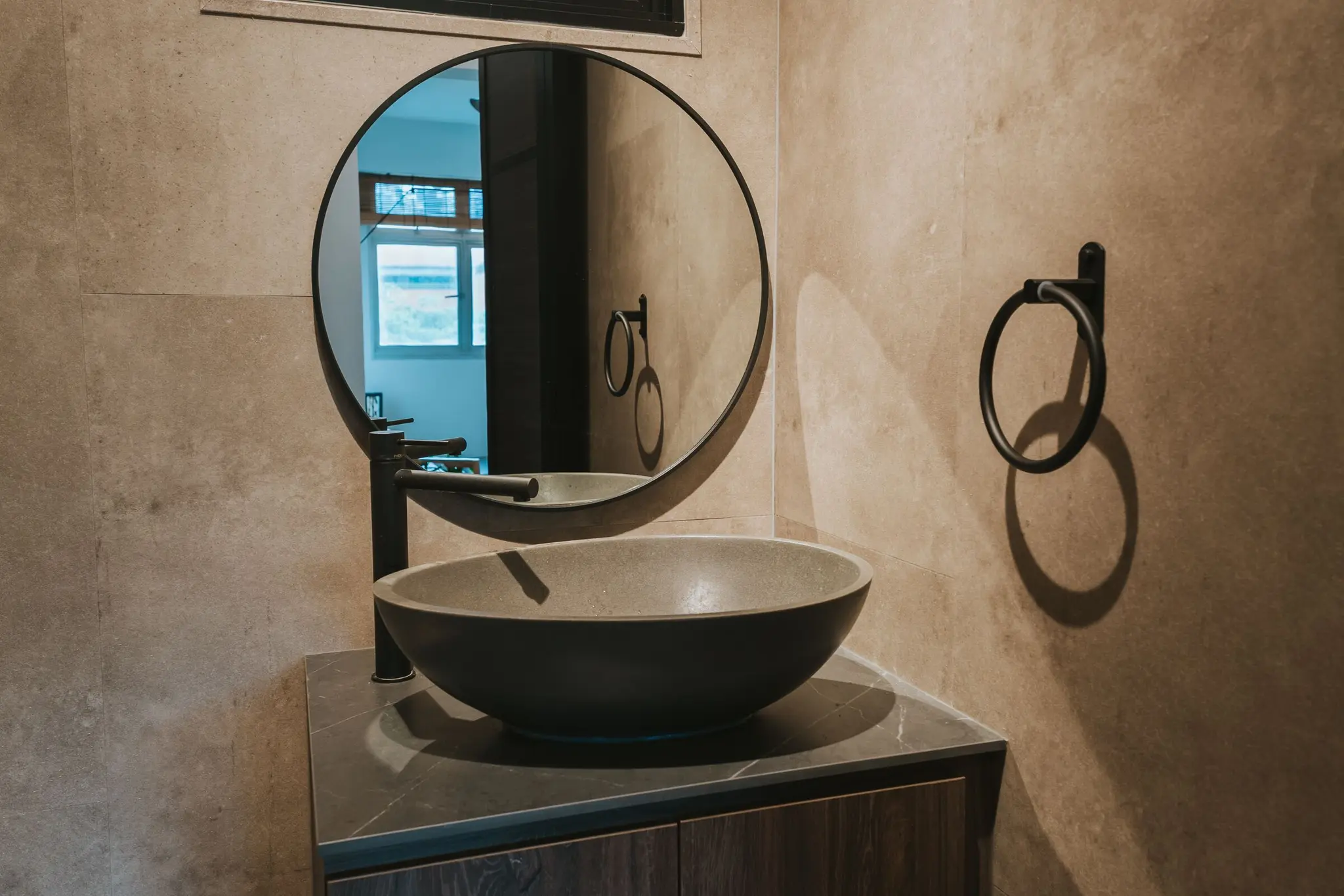 Stone-look bathroom with a round mirror at 213C Punggol Walk