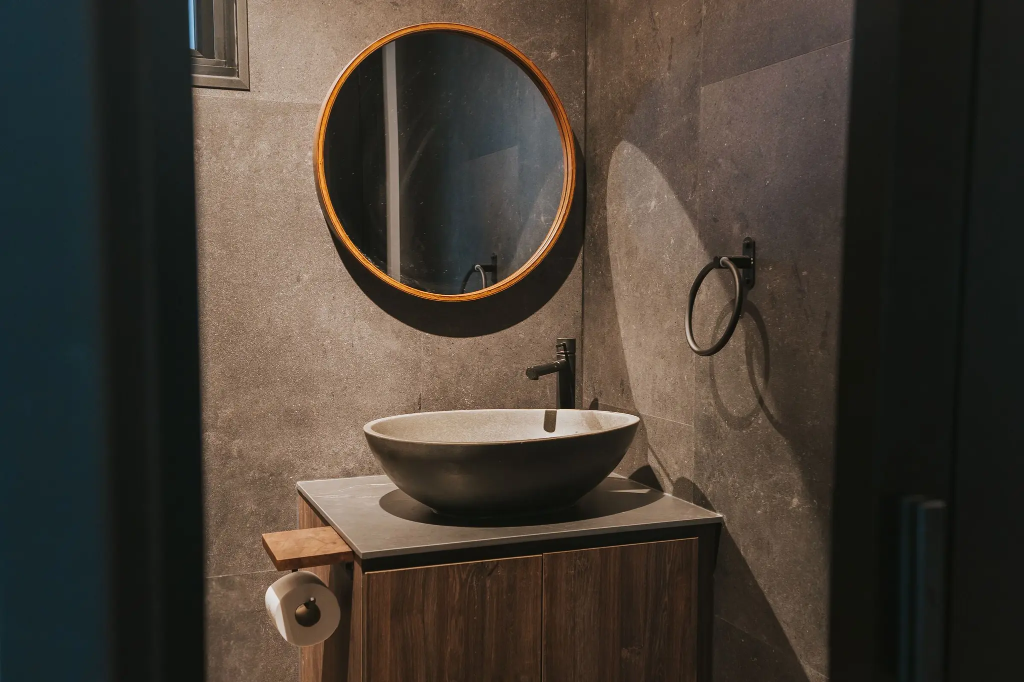 Stone-look bathroom with a round mirror at 213C Punggol Walk