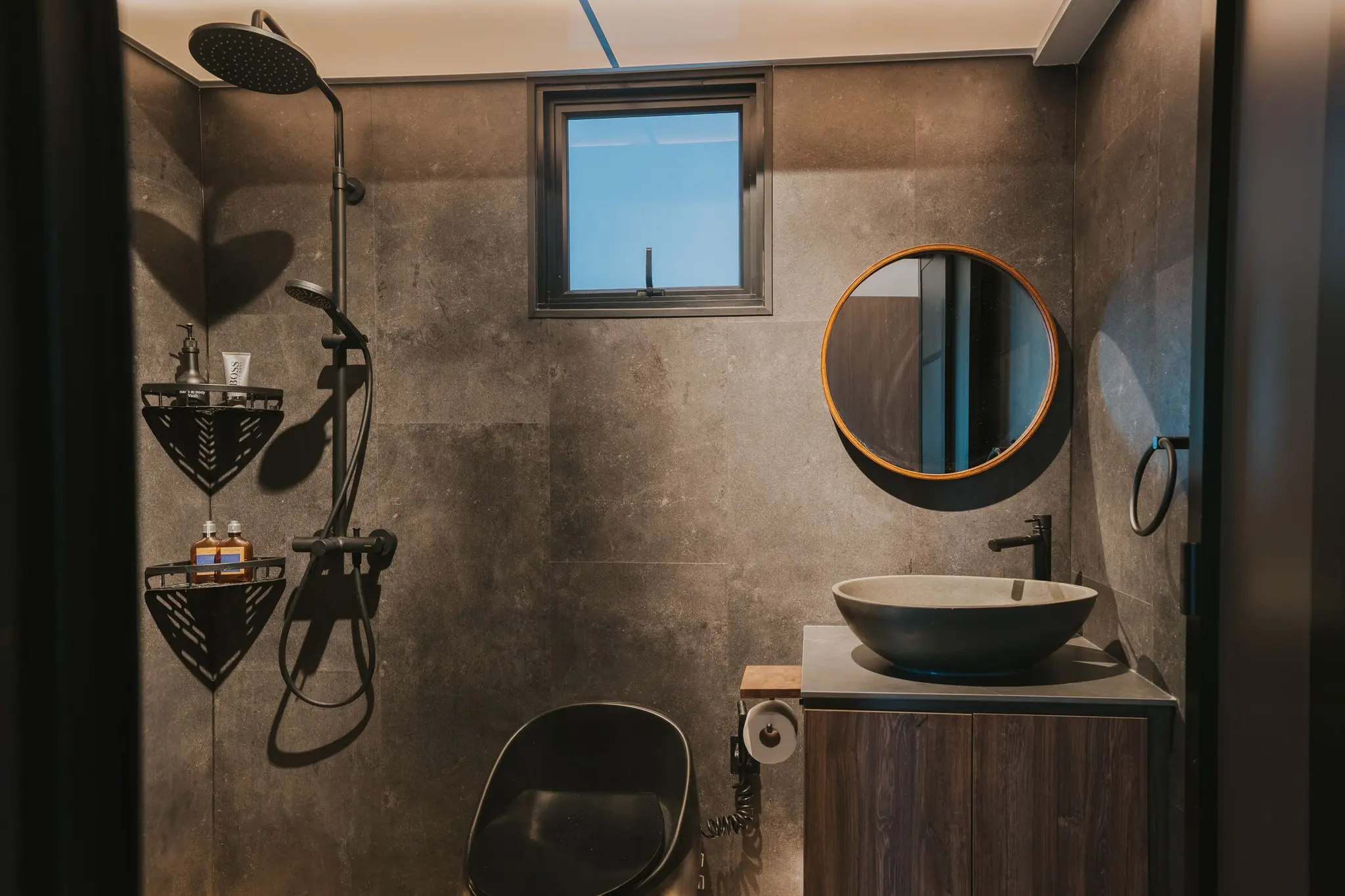Stone-look bathroom with a round mirror at 213C Punggol Walk
