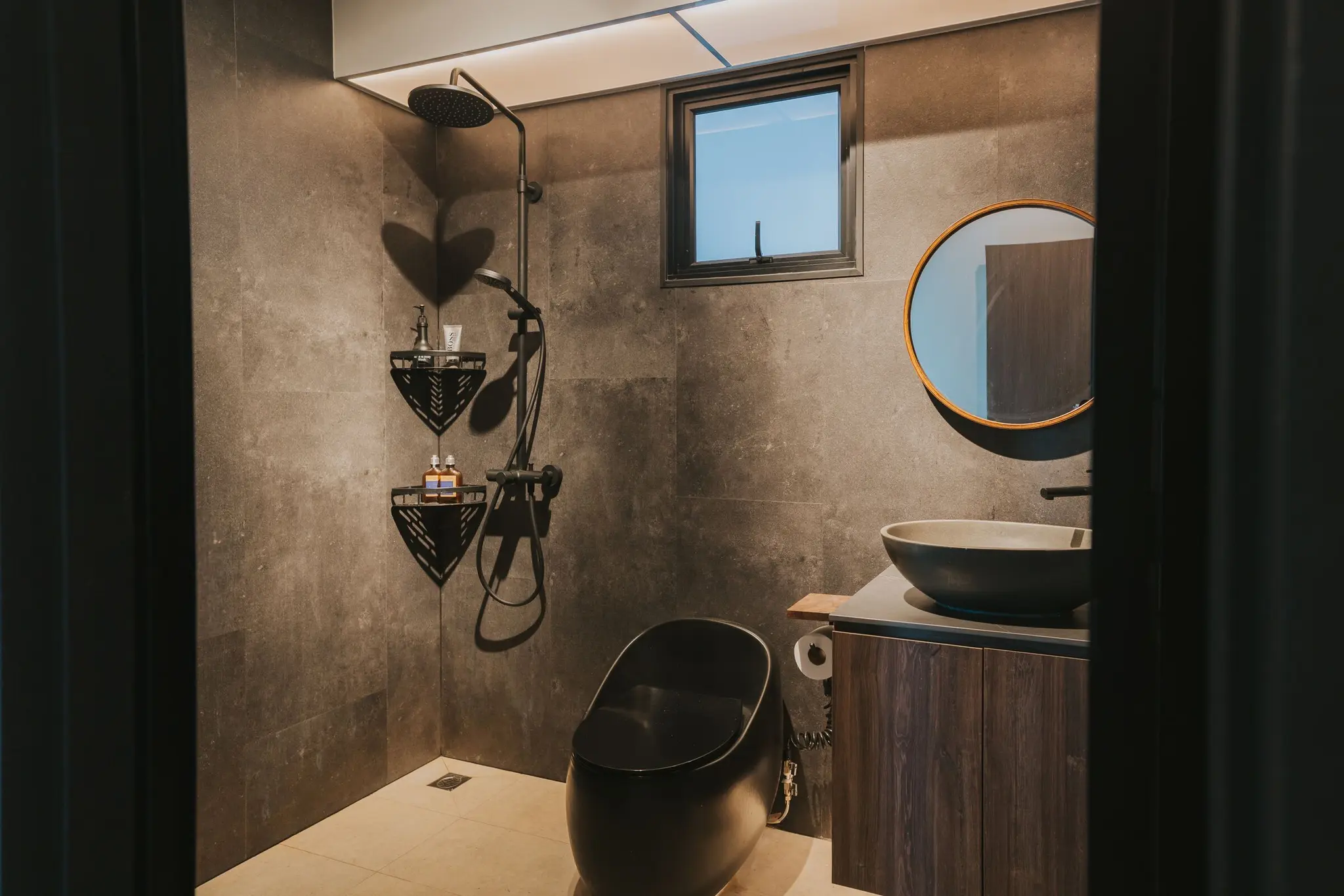 Stone-look bathroom with a round mirror at 213C Punggol Walk