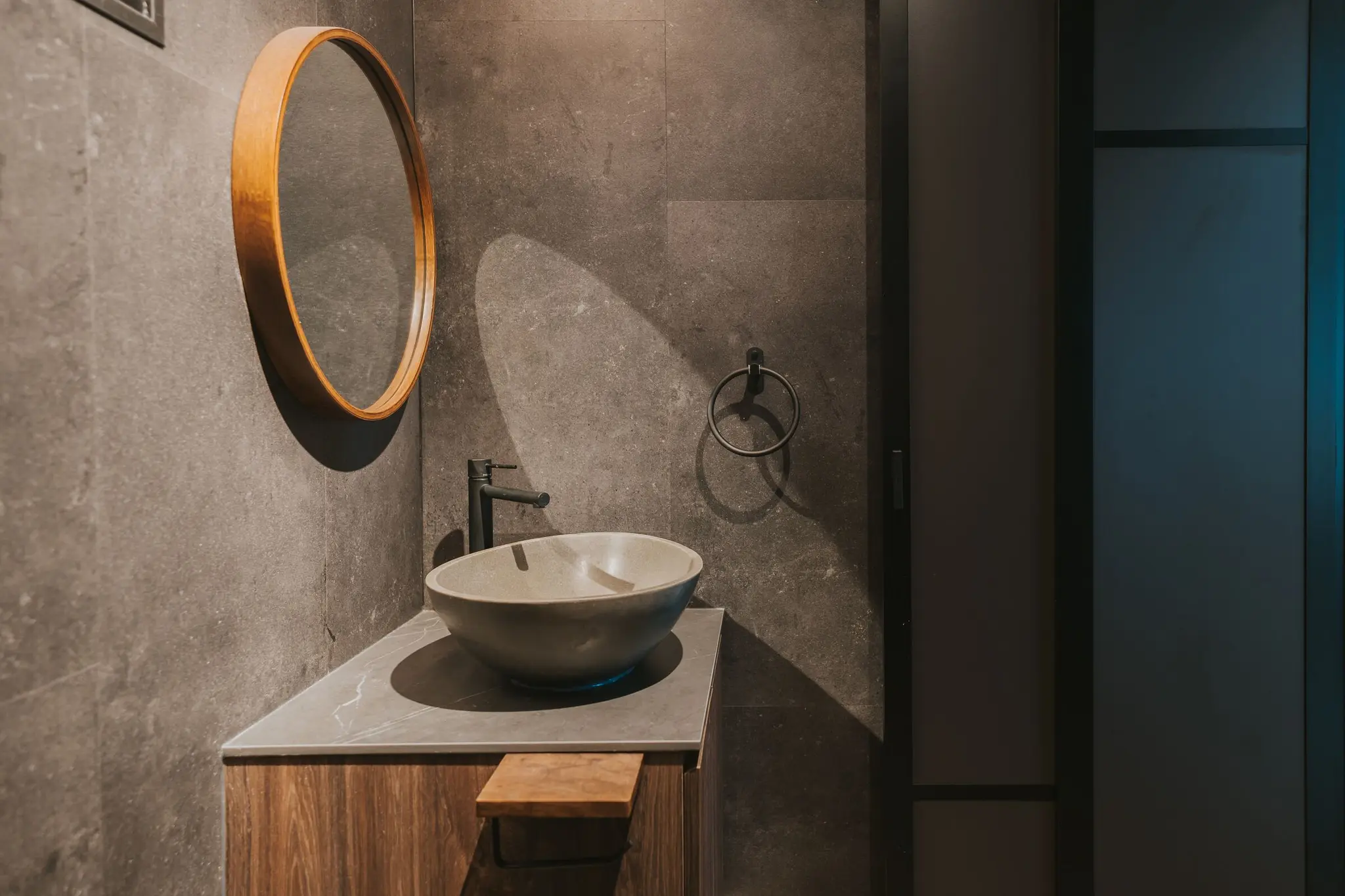Stone-look bathroom with a round mirror at 213C Punggol Walk