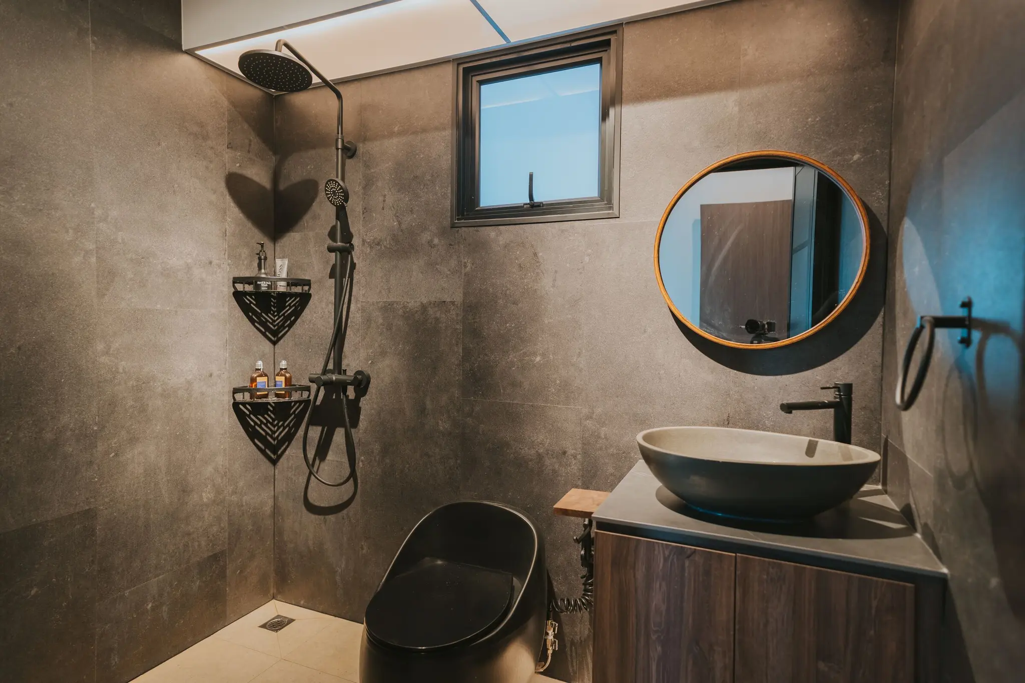 Stone-look bathroom with a round mirror at 213C Punggol Walk