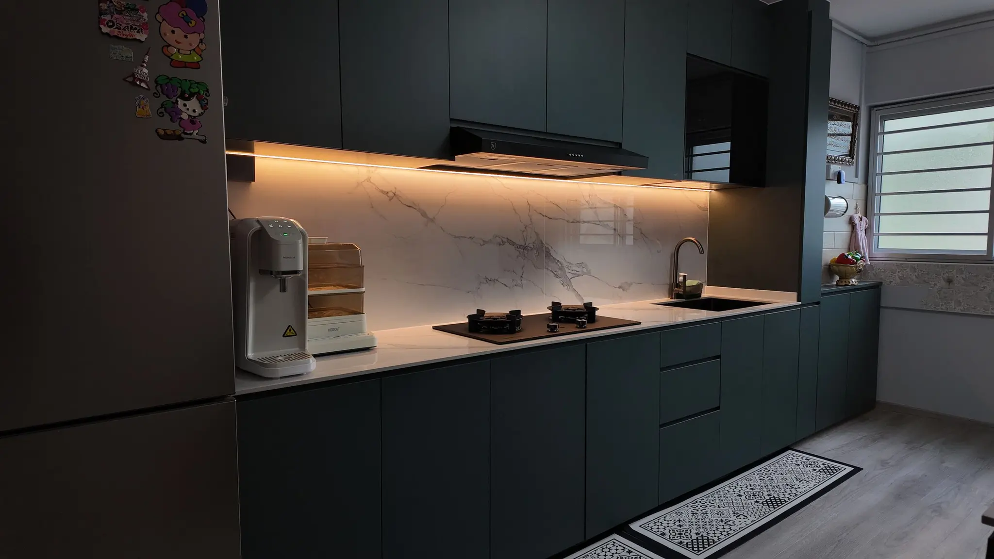 Green kitchen cabinetry and illuminated backsplash at 337 Bukit Batok